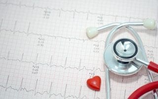 Stethoscope and mini heart on ekg / ecg paper background