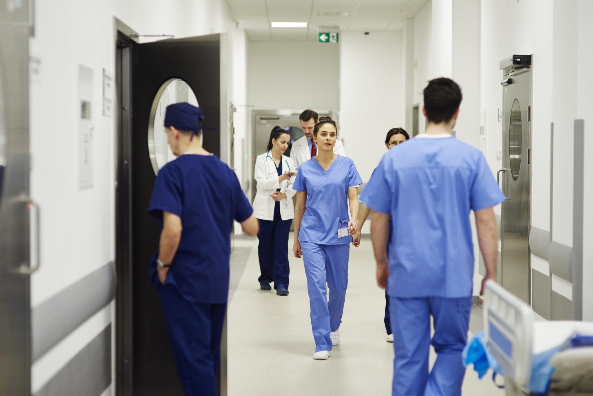Busy nurses and doctors walking through corridor in hospital