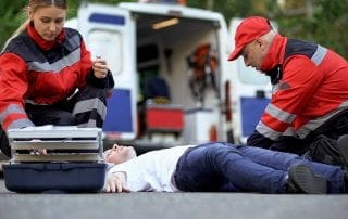 Medics helping man on road, preparing insulin to unconscious diabetic, first aid